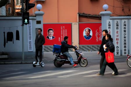 People cross a street beside posters depicting late Chairman Mao Zedong (R) and China's President Xi Jinping in Shanghai, China March 1, 2016. REUTERS/Aly Song/File Photo