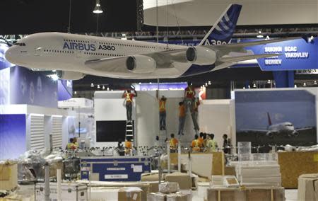 Workers set up exhibition booths near a model of an Airbus A380 aircraft ahead of the Singapore Airshow February 7, 2014. REUTERS/Edgar Su