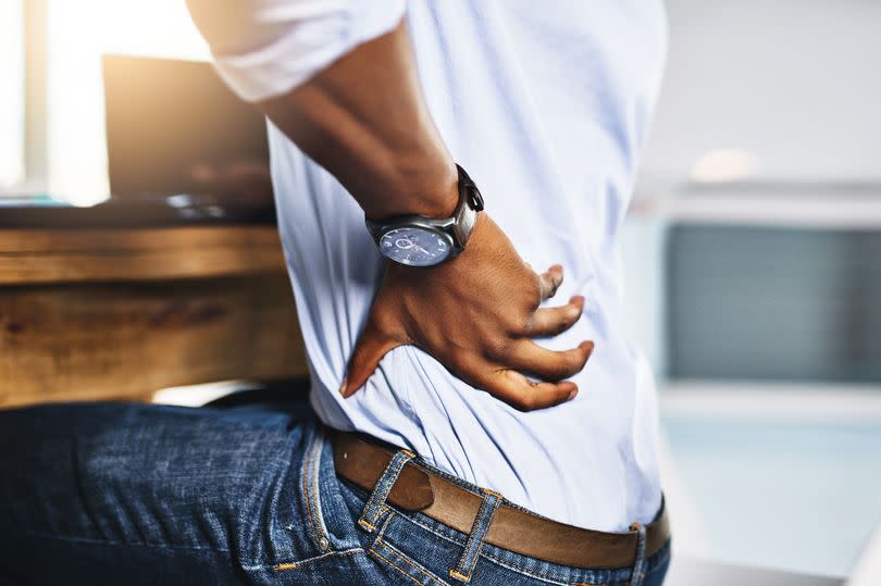 Shot of a unrecognizable businessman suffering from back pains while trying to work in the office