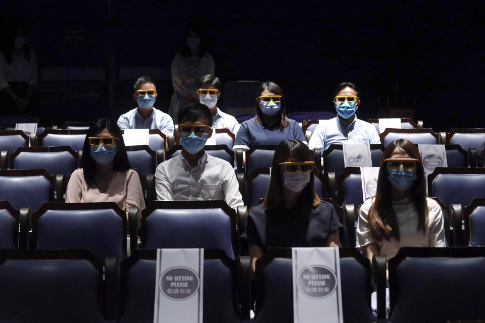 Staff members wearing face masks and 3D glasses as they demonstrate the social distancing in the theatre during a media tour at the Hong Kong's Disneyland on Wednesday, June 17, 2020, a day before the theme park reopen after nearly four months of closure due to the coronavirus pandemic. (AP Photo/Kin Cheung)