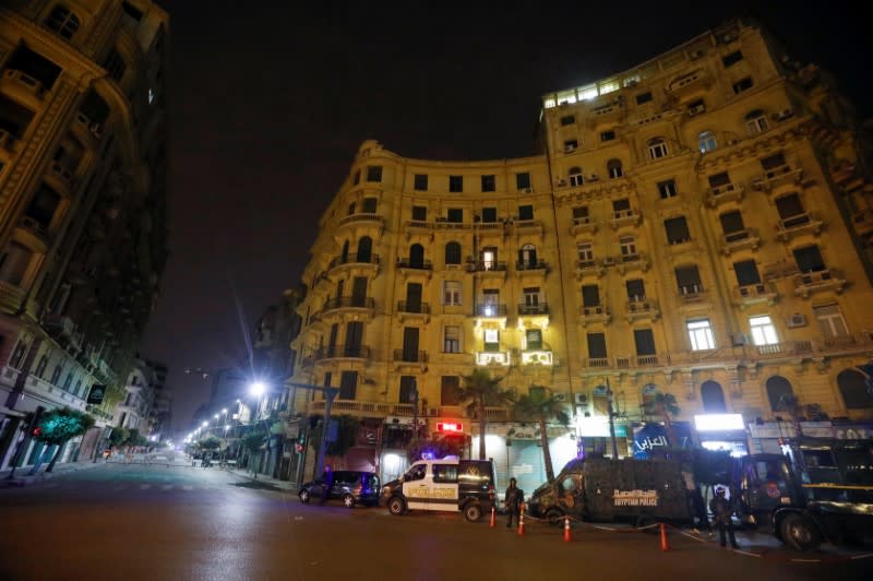 Police members stand near Police vehicles at Talaat Harb square during the first day of a two-weeks night-time curfew which was ordered by the Egyptian Prime Minister Mostafa Madbouly to contain the spread of the coronavirus disease (COVID-19), in Cairo