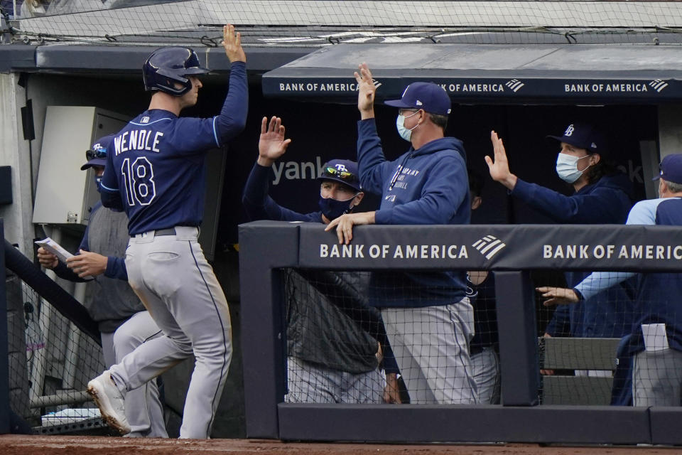 Tampa Bay Rays Joey Wendle (18) is greeted at the dugout after scoring on Yoshi Tsutsugo's RBI double during the seventh inning of a baseball game against the New York Yankees, Sunday, April 18, 2021, at Yankee Stadium in New York. (AP Photo/Kathy Willens)