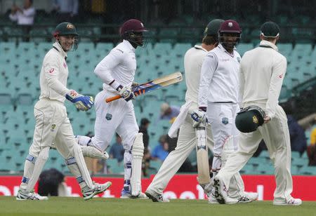 West Indies batsmen Carlos Braithwaite (2nd L) and Denesh Ramdin walk off the pitch amongst Australian players as rain stopped play after three balls in their third cricket test at the SCG in Sydney, January 4, 2016. REUTERS/Jason Reed