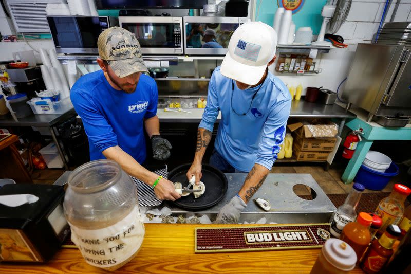 Brandon Martina and Michael Braswell of Lynn's Quality Oysters shuck oysters from Texas for waiting diners at the restaurant in Eastpoint, Florida