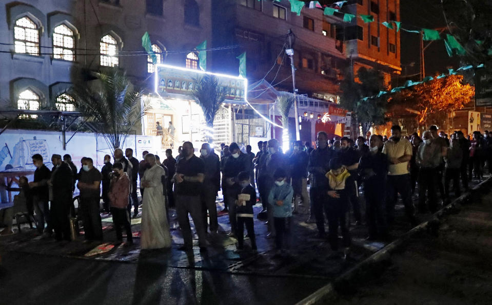 People, some wearing masks to help prevent the spread of the coronavirus, pray the evening prayer during the Muslim holy fasting month of Ramadan, outside a mosque in Gaza City, Tuesday, April 20, 2021. More than a year into the coronavirus pandemic, the worst fears are now coming true in the crowded, blockaded Gaza Strip: A sudden surge in infections and deaths is threatening to overwhelm hospitals weakened by years of conflict and Israeli border closures. (AP Photo/Adel Hana)