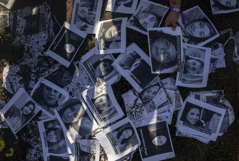 A woman places images of female victims of gender violence on the wet ground during a protest commemorating International Women's Day in Santiago, Chile, on Monday, March 8, 2021. (AP Photo/Esteban Félix)