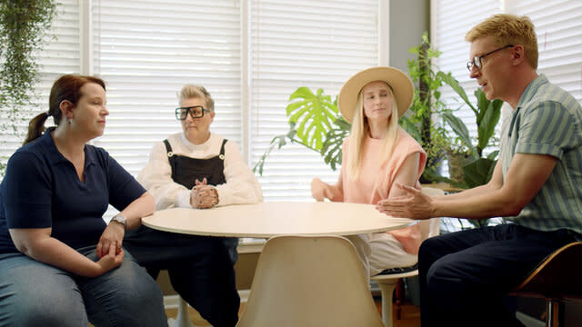 Ella, Katarina, and Johan talk with Lindsey while seated around a dining table.