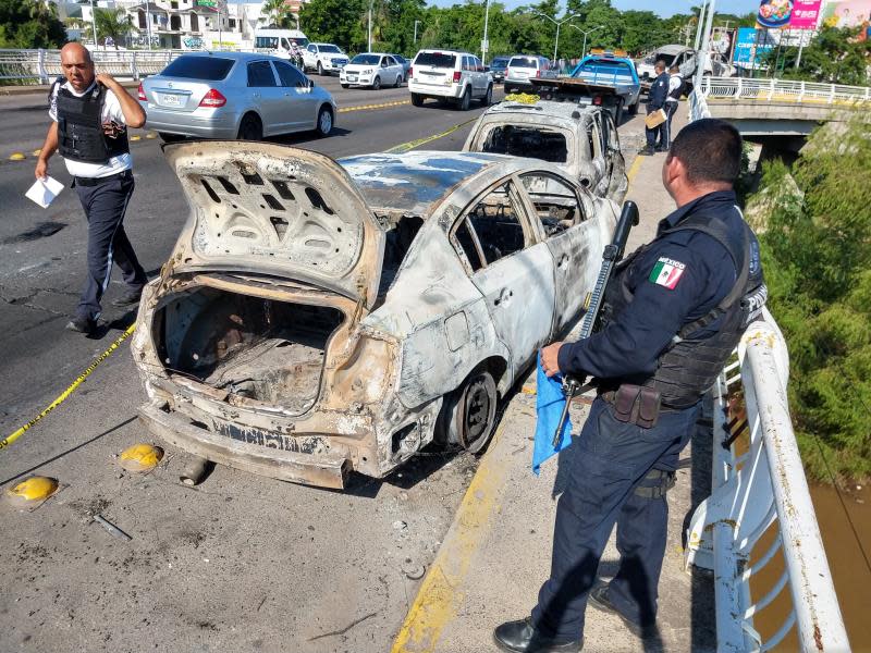 Autoridades trabajan en algunos de lo vehículos calcinados tras los enfrentamientos de ayer de las fuerzas federales con grupos armados este viernes, en la ciudad de Culiacán, en el estado de Sinaloa (México). EFE/ Juan Carlos Cruz