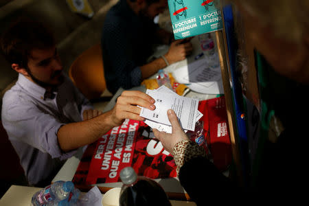 A student gives a ballot to a woman outside the University of Barcelona, while the students inform citizens where they can vote in the banned October 1 independence referendum, in Barcelona, Spain, September 26, 2017. REUTERS/Jon Nazca