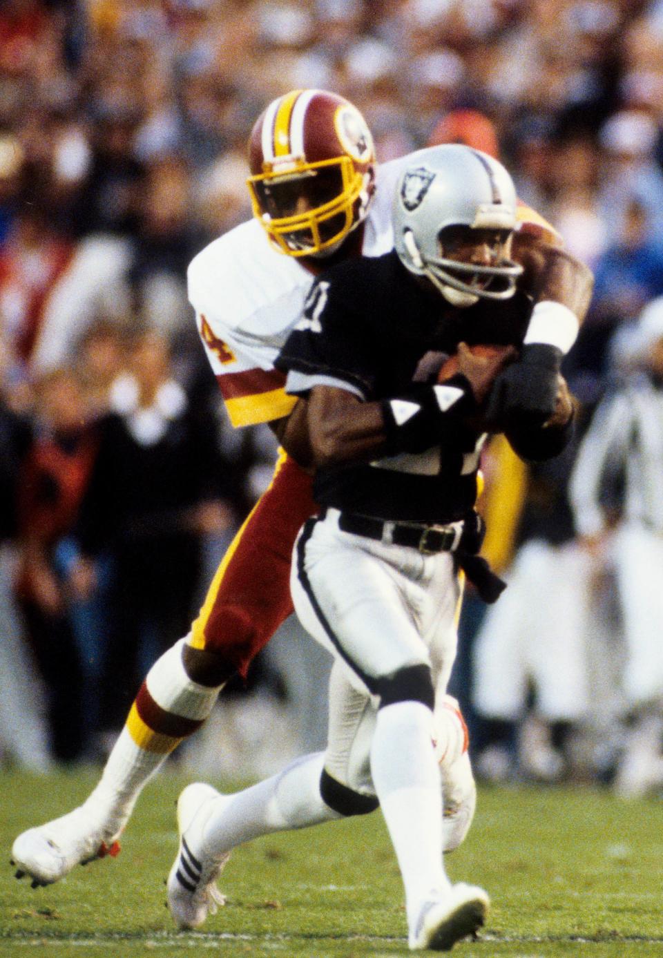 Raiders receiver Cliff Branch resists the tackle of Washington defensive back Anthony Washington during Super Bowl XVIII at Tampa Stadium, Jan. 22, 1984. The Raiders won 38-9.