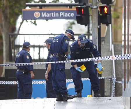 New South Wales police officers wear protective masks as they place marker cones over potential evidence among shattered glass in their investigation into the Sydney cafe siege, December 16, 2014. REUTERS/Jason Reed