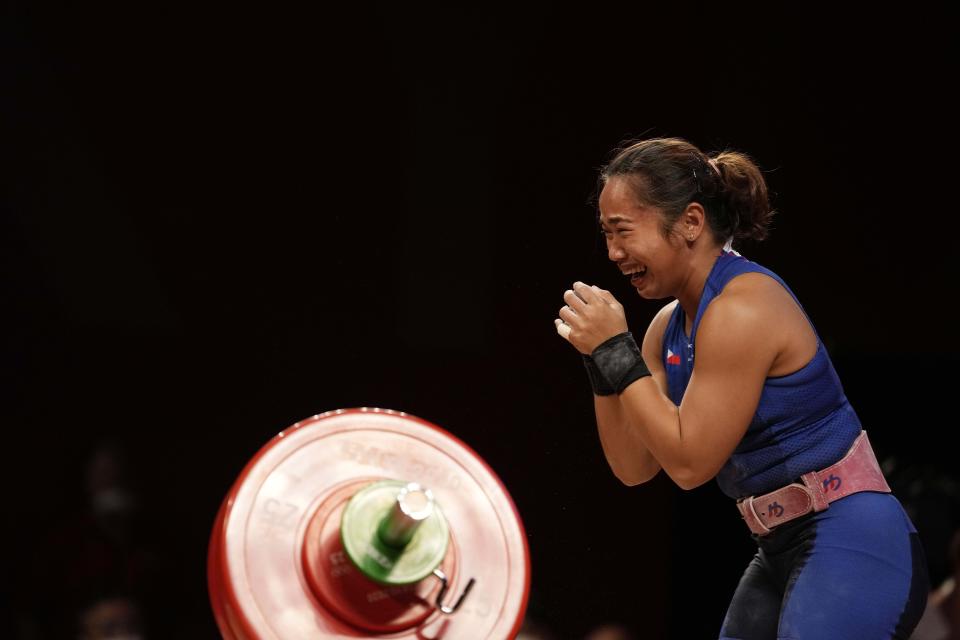 Hidilyn Diaz of Philippines celebrates as she sets the new world record and won the gold medal in the women's 55kg weightlifting event, at the 2020 Summer Olympics, Monday, July 26, 2021, in Tokyo, Japan. (AP Photo/Luca Bruno)