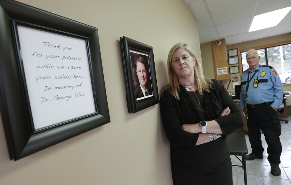 FILE - In this May 19, 2016, file photo, South Wind Women's Center executive director Julie Burkhart stands in the entryway of the Wichita, Kan. abortion clinic which was once owned by slain Dr. George Tiller, pictured at left. Burkhart says she's terrified by the mail-bomb scare that has targeted prominent Democrats, and she's trying to make sure security is tight at the three abortion clinics she operates. (AP Photo/Charlie Riedel, File)