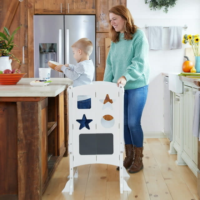 The tower with a toddler standing in it at a kitchen countertop with a model behind