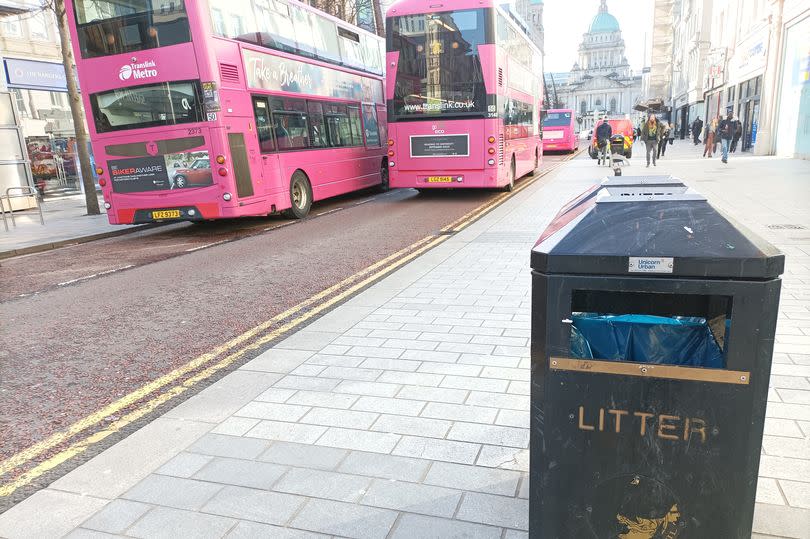 Belfast city centre bin at Donegall Place with buses driving past and City Hall in the distance