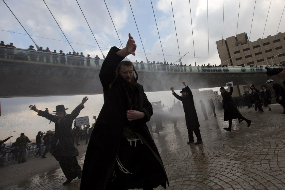 Police officers shoot a water canon at ultra-Orthodox Jewish men during their demonstration in Jerusalem, Thursday, Feb. 6, 2014. Israeli police said thousands of ultra-Orthodox Jews are blocking highways across the country to protest plans to enlist them into the military. (AP Photo/Sebastian Scheiner)