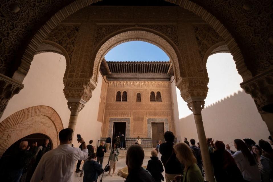 Group of people under an ornate archway, looking toward a building's intricate facade