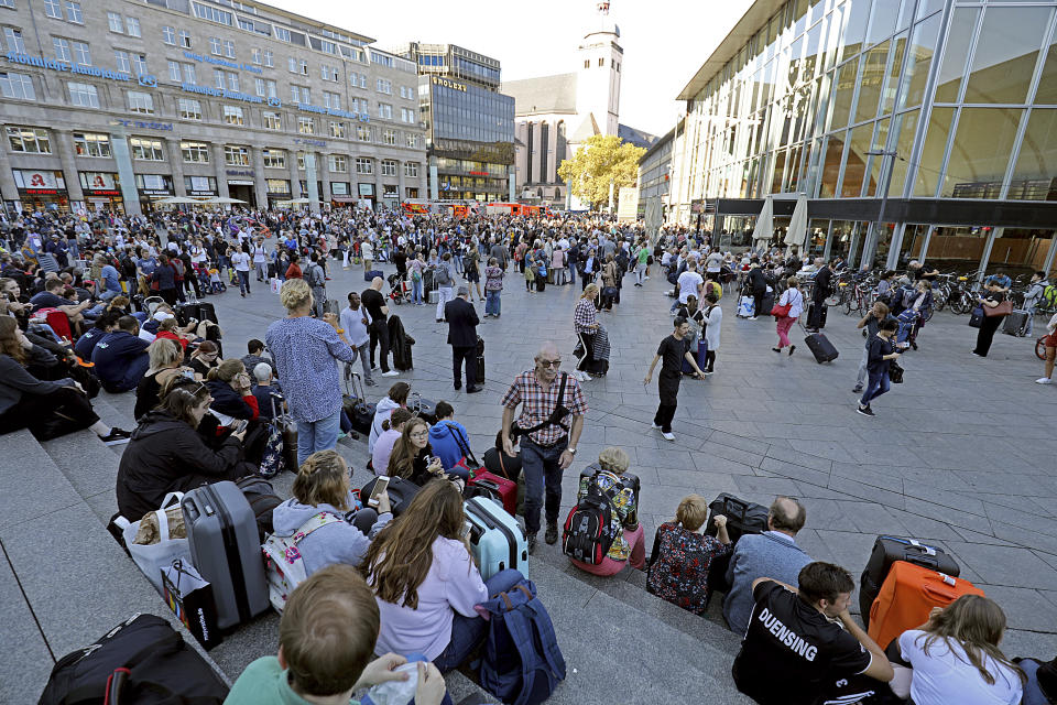 People wait outside the Cologne, western Germany, train station Monday, Oct. 15, 2018. Cologne police closed parts of the western German city’s main train station after a man took a woman hostage in a pharmacy inside. (Oliver Berg/dpa via AP)