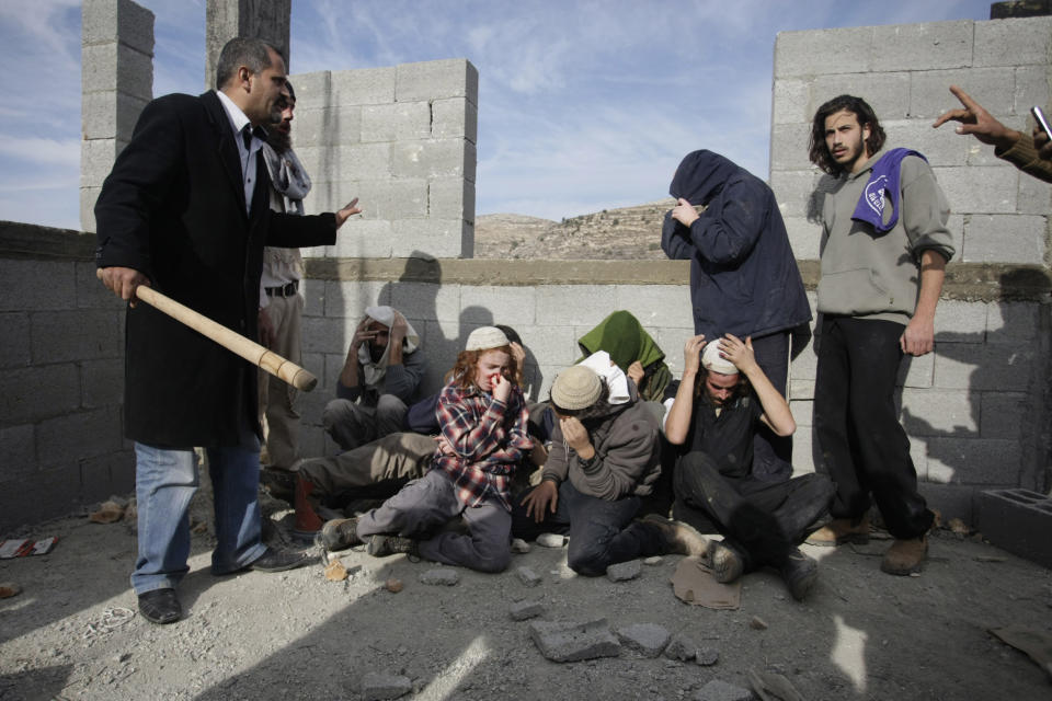 FILE - In this file photo taken Tuesday, Jan. 7, 2014, injured Israeli settlers are detained by Palestinian villagers in a building under construction near the West Bank village of Qusra, southeast of Nablus. The annual rate of Israeli settler attacks against Palestinians has almost quadrupled in eight years, U.N. figures show, buttressing claims that Israeli security forces have largely failed to stem the so-called "price tag" campaign in which thugs cut down trees, deface mosques and beat Palestinian farmers. (AP Photo/Nasser Ishtayeh, File)