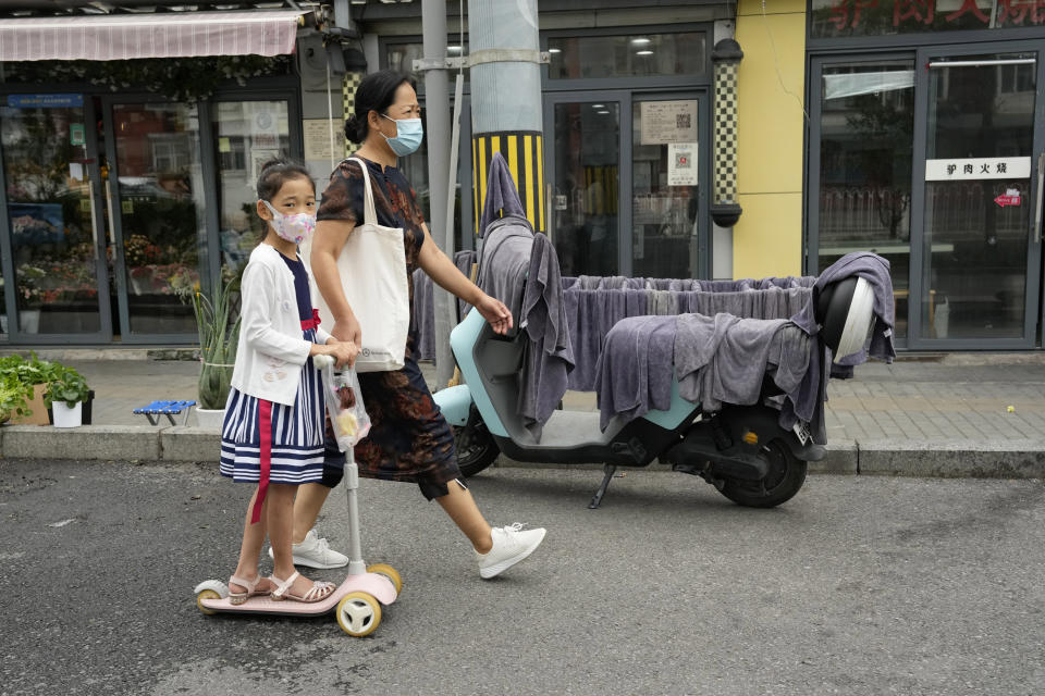 Residents pass by towels hung up to dry on a scooter and a drying rack outside a barber shop in Beijing, Monday, Aug. 15, 2022. China’s central bank trimmed a key interest rate Monday to shore up sagging economic growth at a politically sensitive time when President Xi Jinping is believed to be trying to extend his hold on power. (AP Photo/Ng Han Guan)