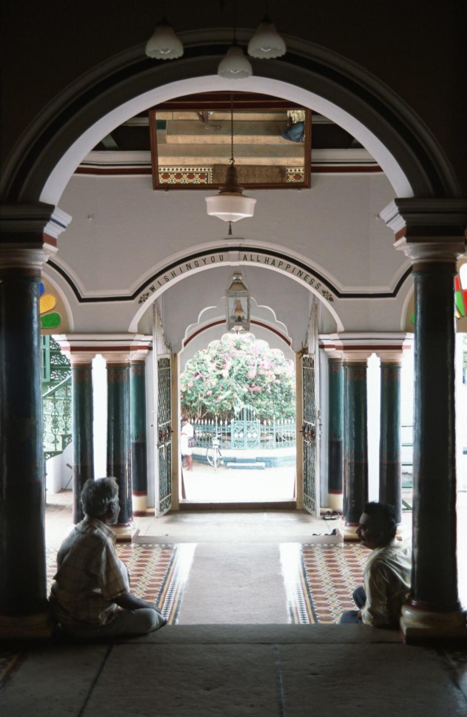Visitors sit at the front entrance of the Raja of Chettinad's mansion, open for public viewing, in Tamil Nadu in 2005.