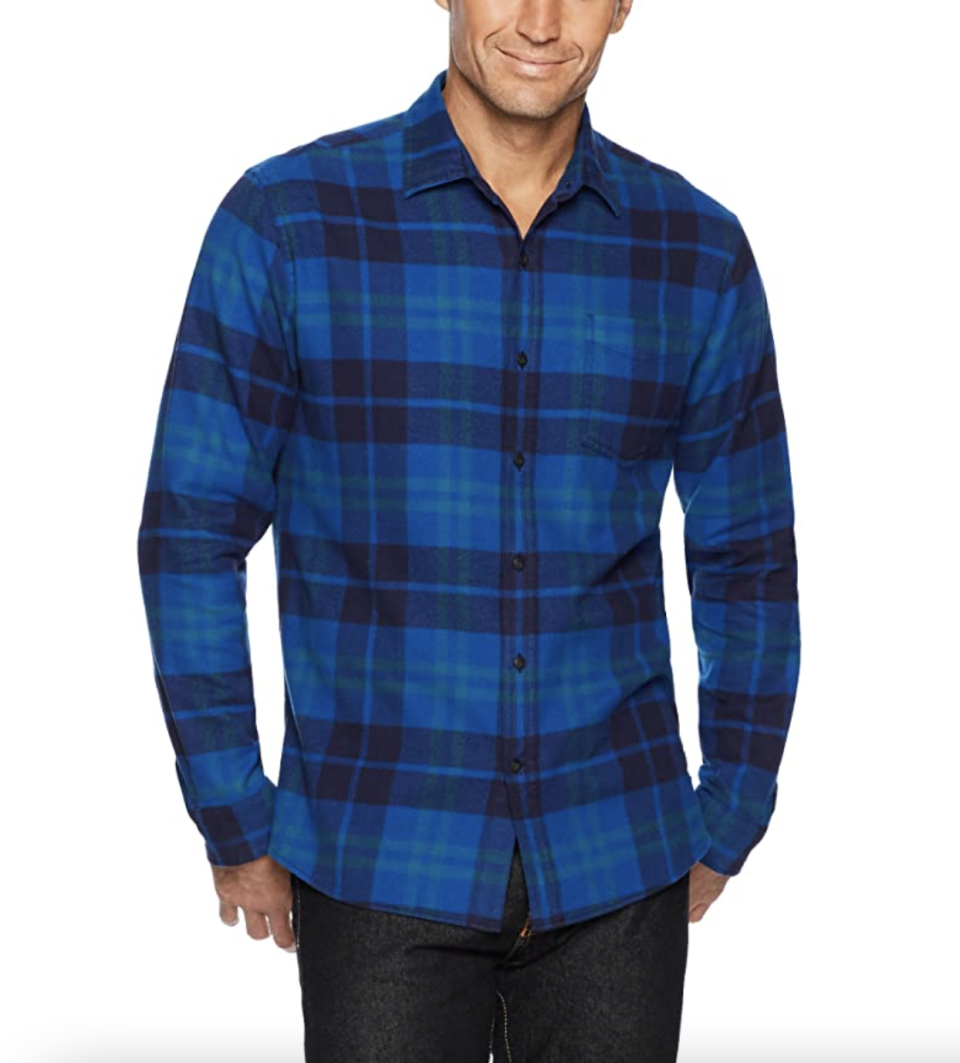 male model with head cut off posing in blue plaid shirt with black jeans and hands in pocket