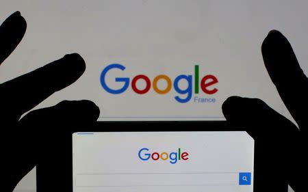 A woman holds her smart phone which displays the Google home page, in this picture illustration taken February 24, 2016. REUTERS/Eric Gaillard/Illustration/Files