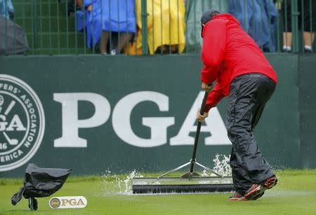A maintenance crew worker attempts to move rain water off the 10th tee during a rain delay at the start of the second round of the 2014 PGA Championship at Valhalla Golf Club in Louisville, Kentucky, August 8, 2014. REUTERS/Brian Snyder