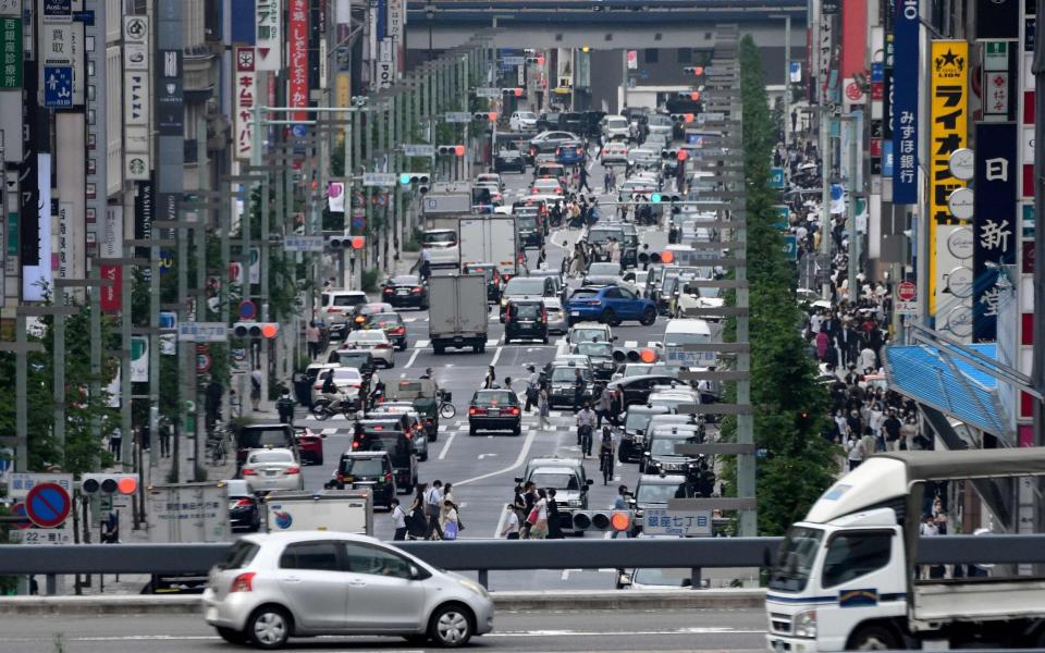 Vehicles and pedestrians move through a street in Tokyo's Ginza shopping district on July 7, 2021, as reports said the Japanese government plans to impose a virus state of emergency in Tokyo during the Olympics. (P - AFP