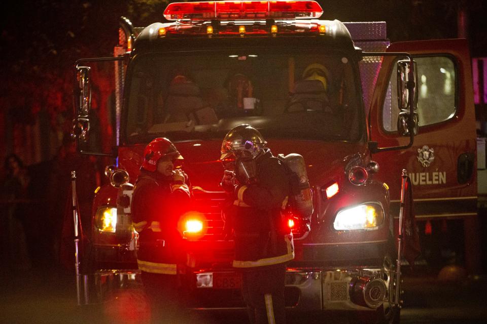 Firefighters prepare to enter an apartment where six Brazilians died of apparent carbon monoxide poisoning in Santiago, Chile, Wednesday, May 22, 2019. Police commander Rodrigo Soto said officers found four adults and two children dead at the six-story building. The fire department said a high concentration of carbon monoxide was measured in the apartment, which it said was completely closed. (AP Photo/Esteban Felix)