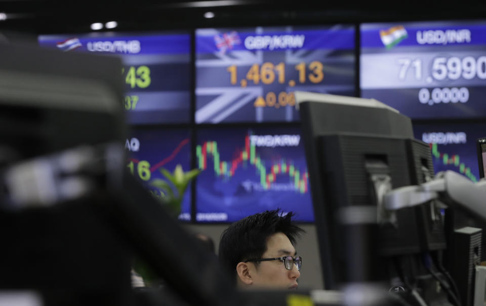 A currency trader watches computer monitors near the screens showing the foreign exchange rates at the foreign exchange dealing room in Seoul, South Korea, Tuesday, Dec. 18, 2018. Asian stocks fell on Tuesday, tracking losses on Wall Street as traders braced for an interest rate hike by Federal Reserve. (AP Photo/Lee Jin-man)