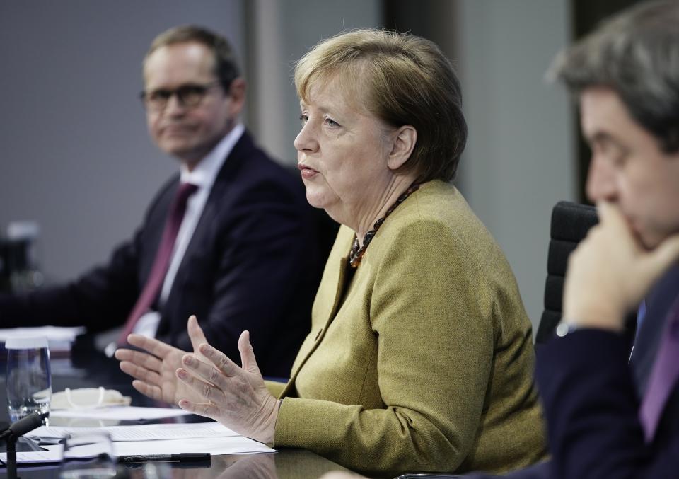 Germany's Chancellor Angela Merkel joins Markus Soeder (CSU), right, Prime Minister of Bavaria and CSU Chairman, and Michael Mueller (SPD), Governing Mayor of Berlin in a press conference following the consultations between the federal and state governments on further COVID measures, in Berlin, Tuesday, Jan. 5, 2021. (Michael Kappeler/pool photo via AP)