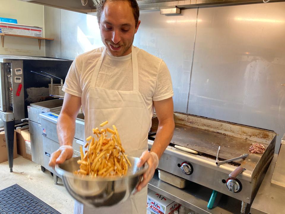 Maudite Poutine co-owner Joe Collier tosses French fries at the Burlington restaurant May 20, 2022.