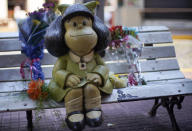 Flower bouquets flank a statue of the comic strip character Mafalda created by Argentine cartoonist Joaquin Salvador Lavado, who was better known as Quino, in Buenos Aires, Argentina, Wednesday, Sept. 30, 2020. Lavado passed away on Wednesday, according to his editor Daniel Divinsky who announced it on social media. He was 88. (AP Photo/Victor R. Caivano)