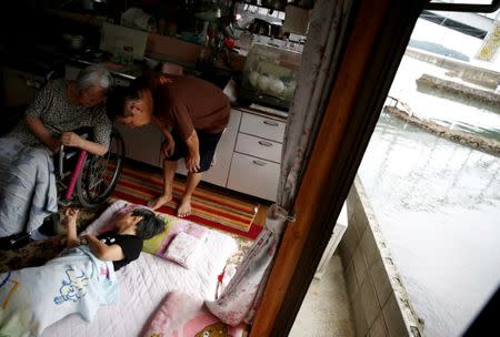 The sister and brother-in-law of Minamata disease patient Jitsuko Tanaka, 64, take care of her as she lies in bed at their home in Minamata, Kumamoto Prefecture, Japan, September 12, 2017. REUTERS/Kim Kyung-Hoon