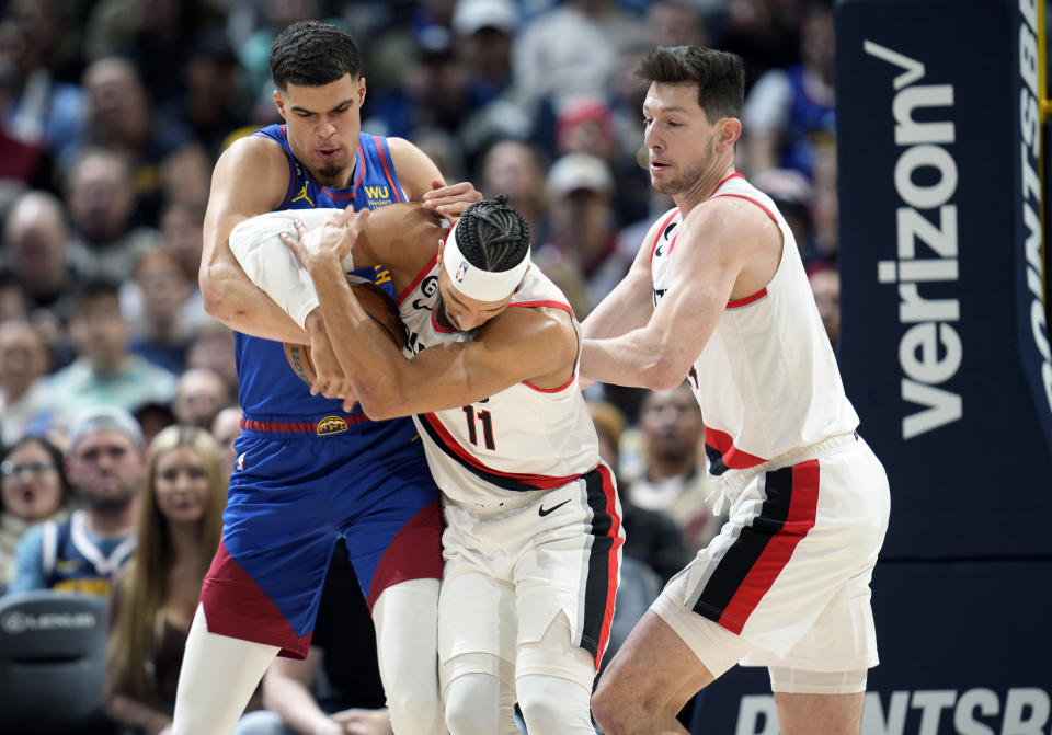 From left, Denver Nuggets forward Michael Porter Jr. fights for control of a loose ball with Portland Trail Blazers guard Josh Hart and forward Drew Eubanks in the first half of an NBA basketball game Friday, Dec. 23, 2022, in Denver. (AP Photo/David Zalubowski)