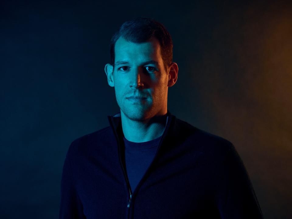 Headshot of Maximilian Winter of Harmonix Fund wearing a navy zip sweater against a blue background