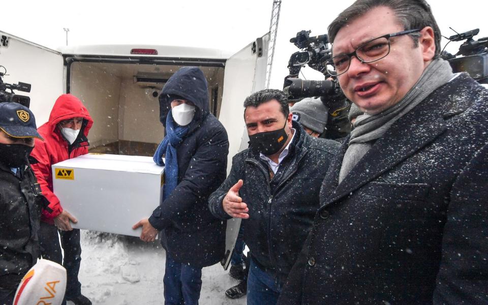 wo workers (L) carry a box with 8,000 doses of the Pfizer-BioNTech vaccine against the coronavirus disease (COVID-19) donated by Serbian President Aleksandar Vucic (R) to North Macedonia's Prime Minister Zoran Zeav (2-R - Shutterstock