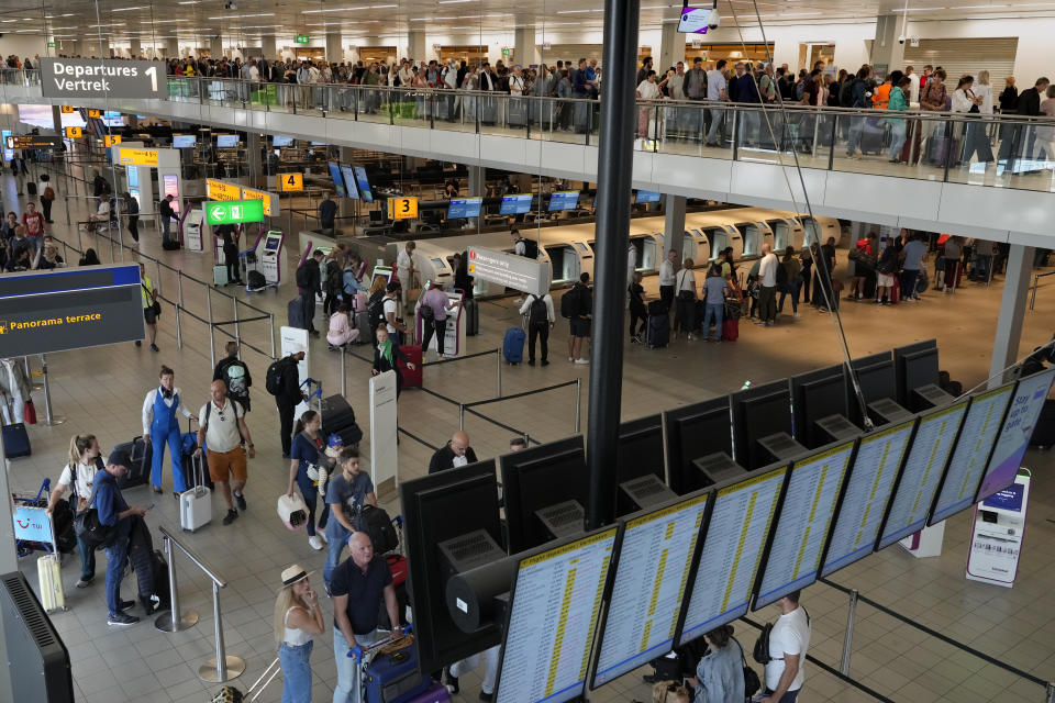 FILE - Travelers wait in long lines to check in and board flights at Amsterdam's Schiphol Airport, Netherlands, on June 21, 2022. Amsterdam’s Schiphol Airport has launched a compensation scheme for travelers who missed their flights because of lengthy delays that have plagued the busy European aviation hub for months. Schiphol announced the scheme Thursday night, Aug. 11, 2022, heading off a possible mass claim for compensation by passengers who saw their holiday plans evaporate amid hours-long delays for pre-flight security screening. (AP Photo/Peter Dejong, File)