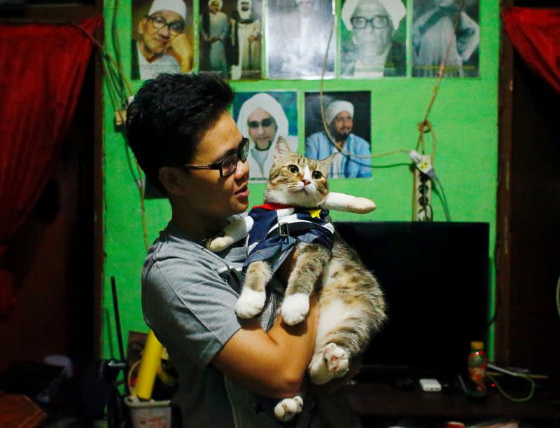 Risma Sandra Irawan, 31, carries her cat wearing a cosplay costume, in Jakarta