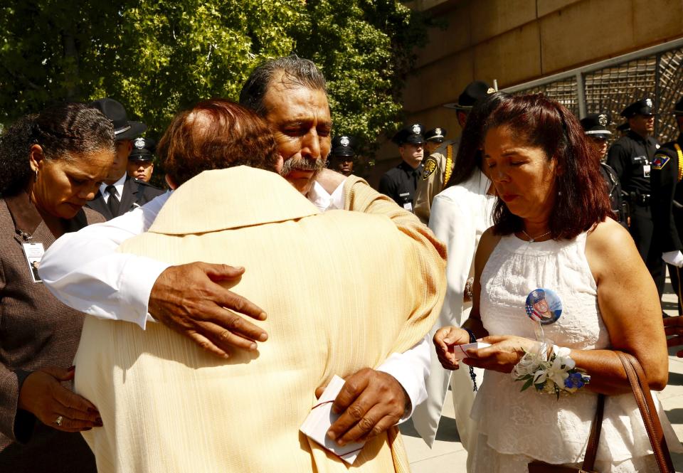 Rocio and Canderlario Diaz, the mother and father of slain Los Angeles Police officer Juan J. Diaz, hug a member of the clergy following a memorial service for their son, LAPD officer Juan Diaz at the Cathedral of Our Lady of the Angels in Los Angeles, Calif., on Monday, Aug. 12, 2019. (Al Seib/Los Angeles Times via AP)