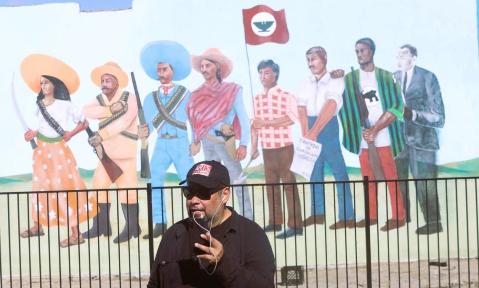 Hugo Hopping graba un audio delante del mural revivido que su padre, Antonio Bernal, pintó en 1968 cuando era miembro del Teatro Campesino en Del Rey. El 22 de octubre de 2023 se celebró una ceremonia en memoria de Bernal.