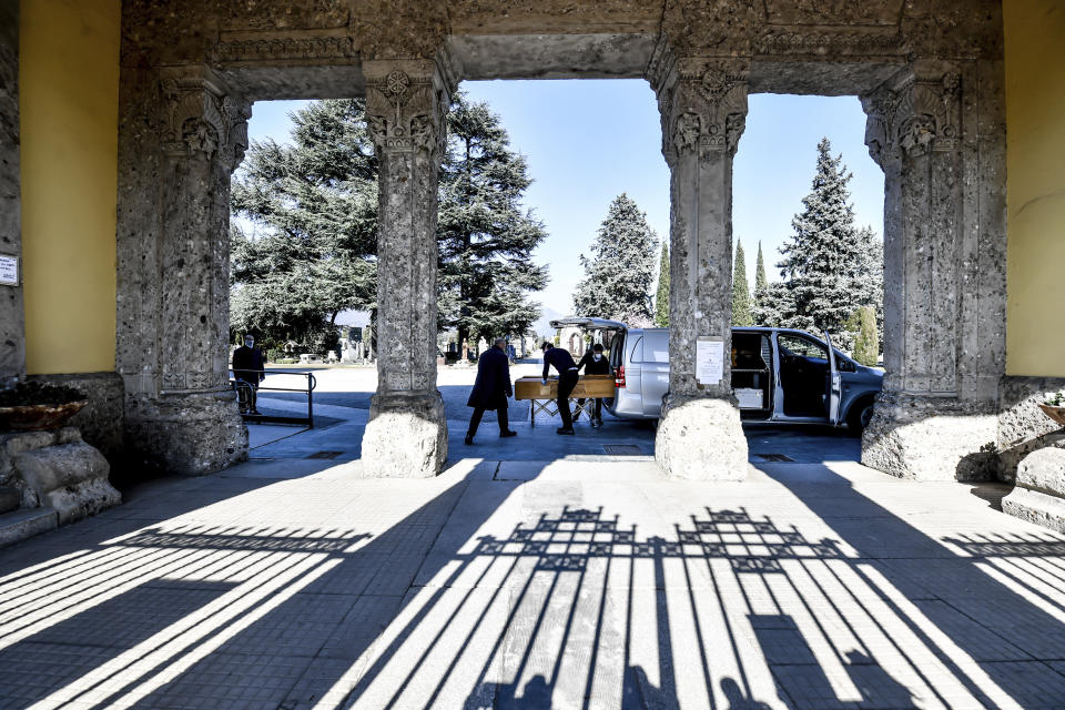 Undertakers carry a coffin out of a hearse at Bergamo's cemetery, northern Italy, Monday, March 16, 2020. Bergamo is one of the cities most hit by the new coronavirus outbreak in northern Italy. For most people, the new coronavirus causes only mild or moderate symptoms. For some it can cause more severe illness, especially in older adults and people with existing health problems. (Claudio Furlan/LaPresse via AP)