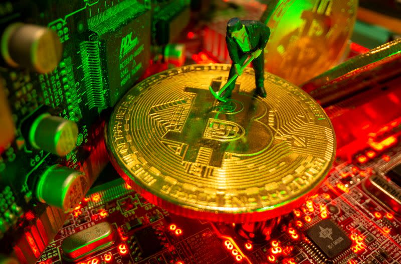 FILE PHOTO: A small toy figure and representations of the virtual currency Bitcoin stand on a motherboard in this picture illustration