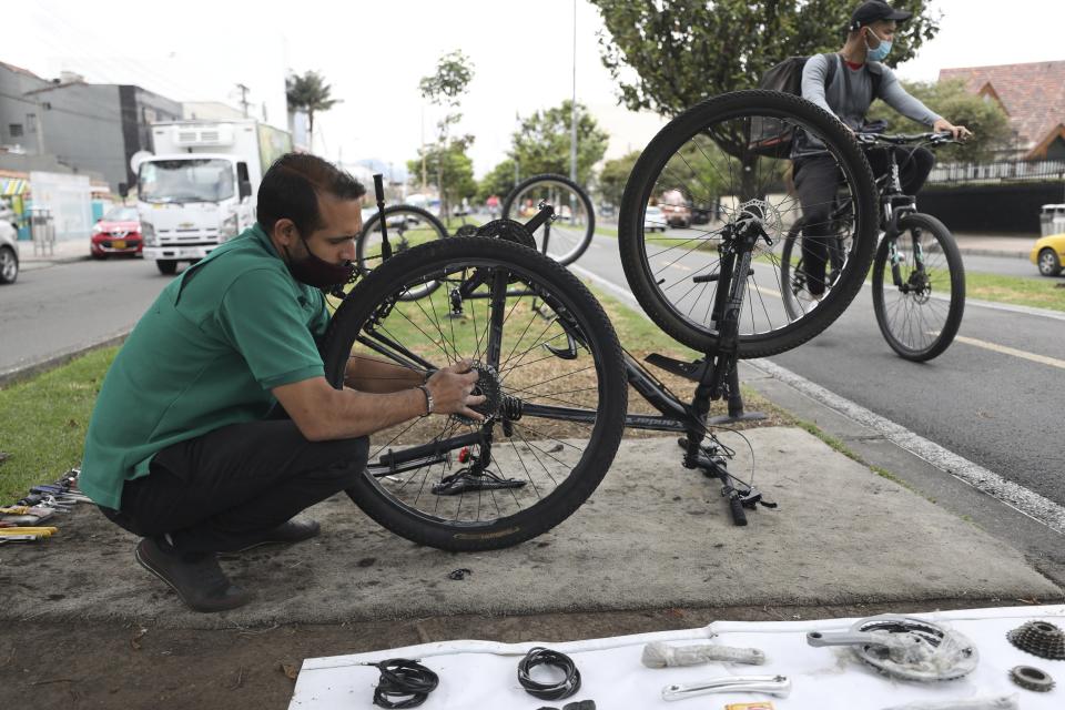 Venezuelan Michael Ostis, 33, repairs a bicycle, in Bogota, Colombia, Tuesday, Feb. 9, 2021. Colombia said Monday it will register hundreds of thousands of Venezuelan migrants and refugees currently in the country without papers, in a bid to provide them with legal residence permits and facilitate their access to health care and legal employment opportunities. (AP Photo/Fernando Vergara)