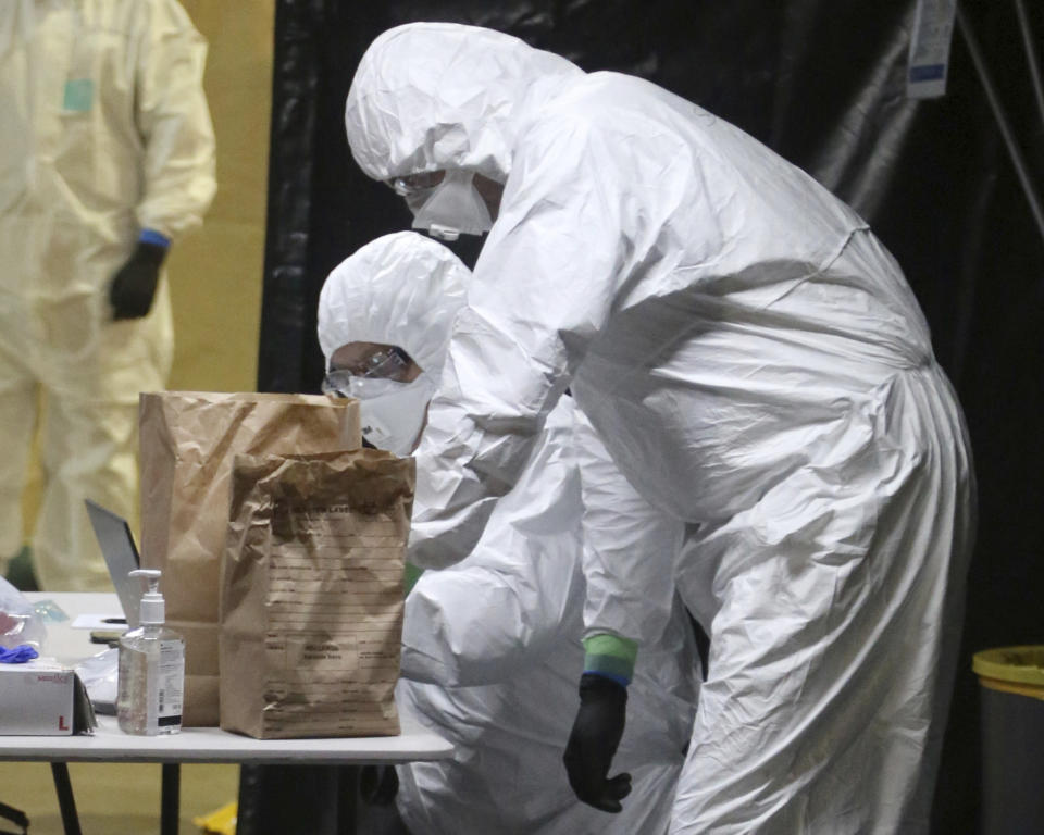In this Wednesday, April 8, 2020, photo provided by the New South Wales Police, investigators in protective gear examine material from the Ruby Princess cruise ship at Wollongong, Australia. Police boarded the cruise ship to seize evidence and question crew members after the vessel was linked to hundreds of COVID-19 cases and more than a dozen deaths across Australia. (Nathan Patterson/NSW Police via AP)