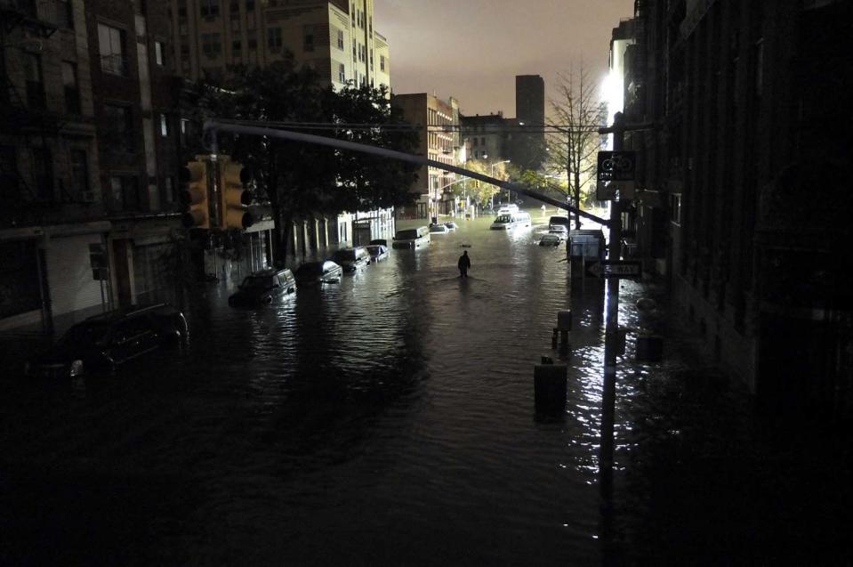 Un hombre camina en medio de los autos sumergidos, durante un apagón que se presentó en la avenida C con 7th St, en Manhattan, New York, en los primeros momentos del paso del huracán Sandy, el 30 de octubre de 2012. Christos Pathiakis/Getty Images