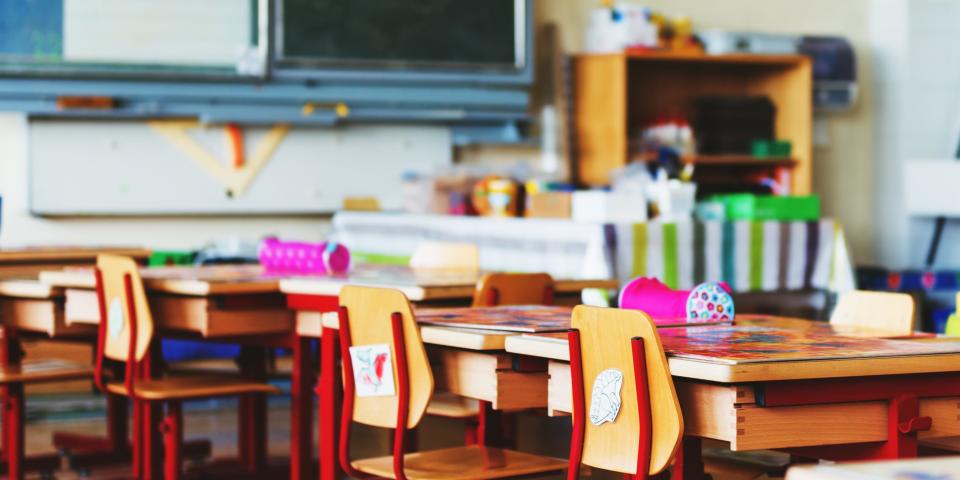 A colorful classroom with chairs, desks, supplies, and a blackboard.