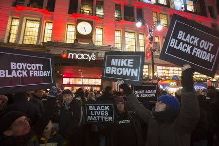 Protesters hold signs aloft outside Macy's before the kick off of Black Friday sales in New York November 27, 2014. REUTERS/Andrew Kelly