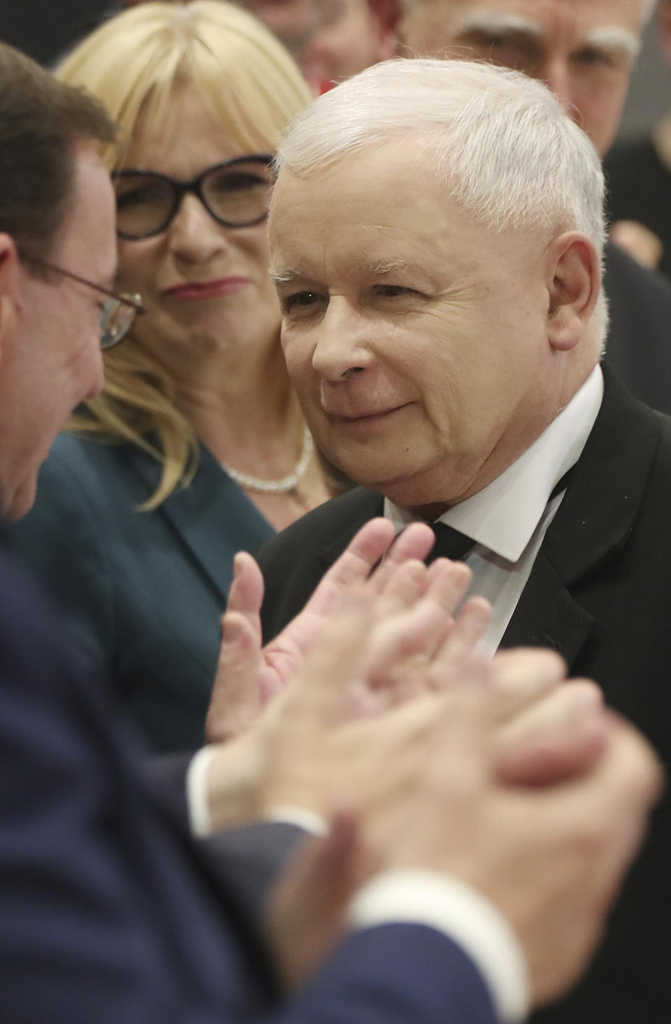 In this photo taken Tuesday Oct. 8, 2019 Poland's ruling right-wing party leader Jaroslaw Kaczynski,center, is applauded by party members after he spoke at a conventionin in Warsaw, Poland, ahead of Sunday parliamentary election in which his Law and Justice party is hoping to win a second term in power. (AP Photo/Czarek Sokolowski)